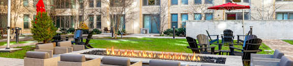 A patio with chairs and a fire pit in front of a building.