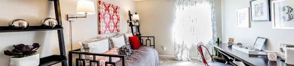 Furnished bedroom with daybed, desk, and plants on shelves at CASA GRANDE APARTMENT HOMES, California, 90630