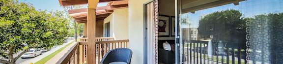 Sunny balcony with patio furniture and large sliding glass door at CASA GRANDE APARTMENT HOMES, Cypress, California