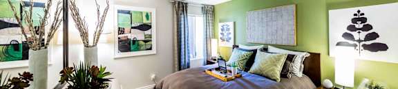 Bedroom with dresser and nightstand with breakfast tray on bed at CASA GRANDE APARTMENT HOMES, Cypress, California