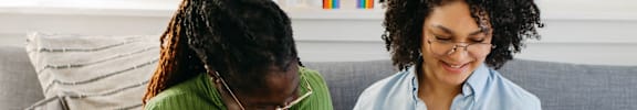 Women Sitting on Couch Looking at Laptop Together