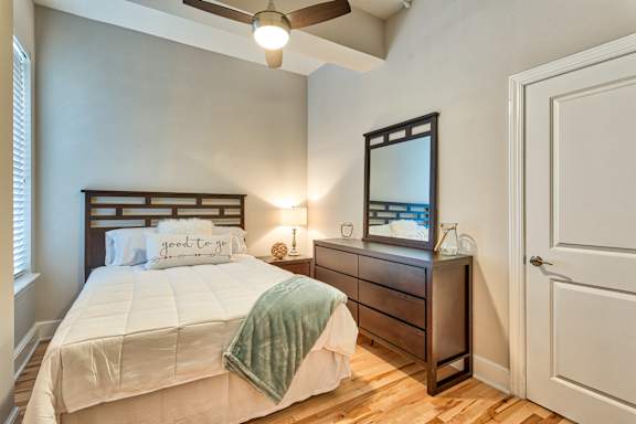 A bedroom with a bed, dresser, and mirror.