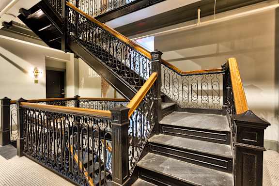 A staircase with a black metal railing and wooden steps.