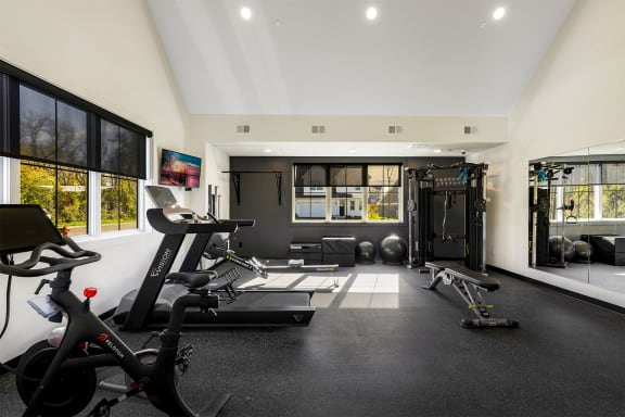 a gym with treadmills and weights in a large room with windows
