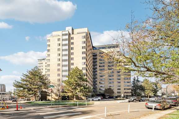 A large beige building with a parking lot in front of it.