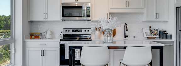 A kitchen with white cabinets and a black stove top oven.