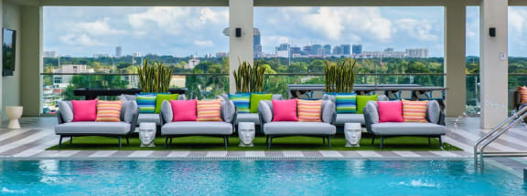 a lounge area next to a pool with a view of the city