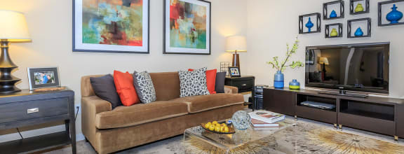 a living room with a brown couch and colorful pillows