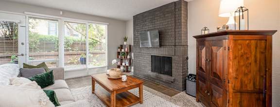 A living room with a grey couch, a wooden coffee table, a fireplace, and a TV mounted on the wall.
