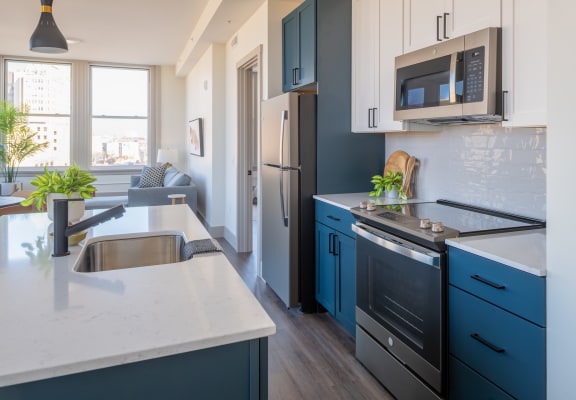 a kitchen with blue cabinets and white countertops at The Nicholas, St Louis, MO 63104