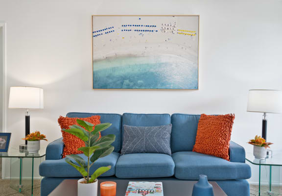 a living room with a blue couch and orange pillows
