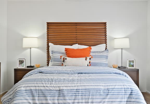 a bedroom with a bed with blue and white bedding and an orange pillow