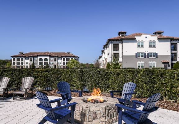 a firepit with blue adirondack chairs on a wooden deck