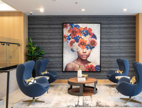 a lobby with blue chairs and a painting of a woman with flowers on the wall