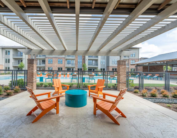 a patio with a table and chairs and a pool in the background