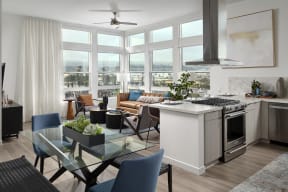 a living room and kitchen with a large window and a table with chairs