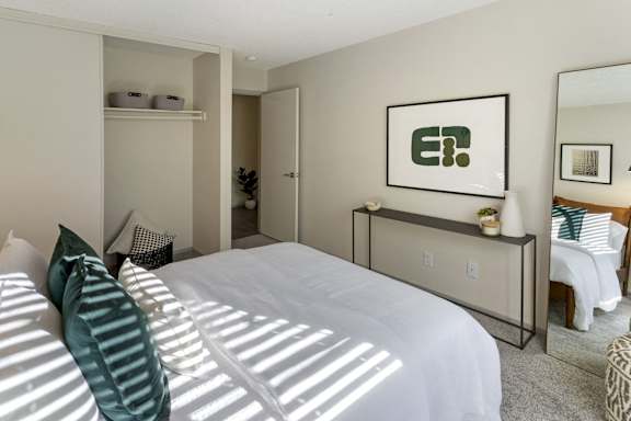 A bedroom with a large bed and a mirror on the wall.