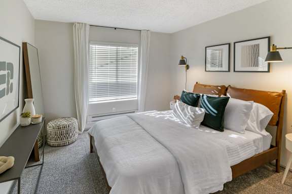 A bedroom with a large bed and a window with blinds.