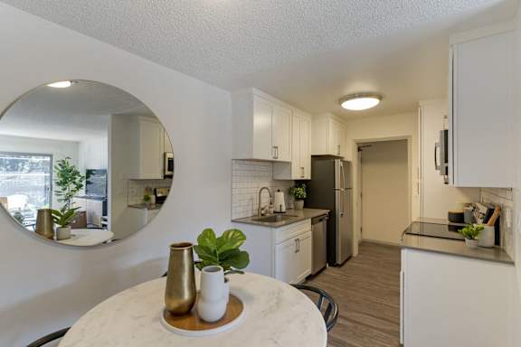 A kitchen with a round table and a mirror on the wall.