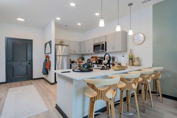 A kitchen with a white island and wooden bar stools.