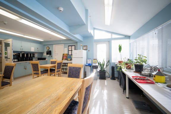 a room with a table and chairs and a kitchen in the background