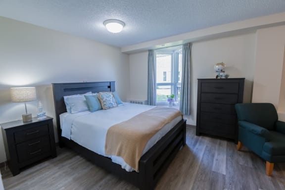 a bedroom with a bed and a chair in a room