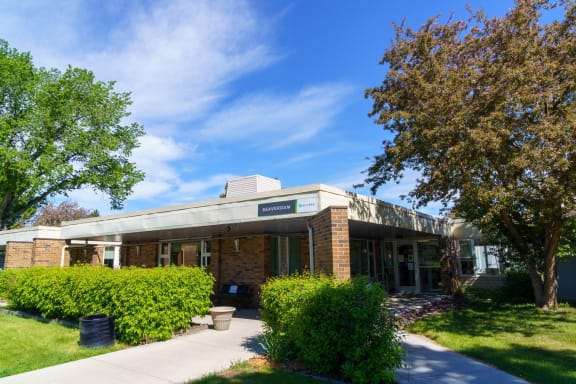 a brick building with a white roof and a large tree in front of it