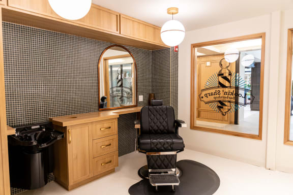 a salon room with a black chair and a black and white tiled wall