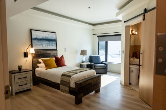 a bedroom with a bed and a chair in a room