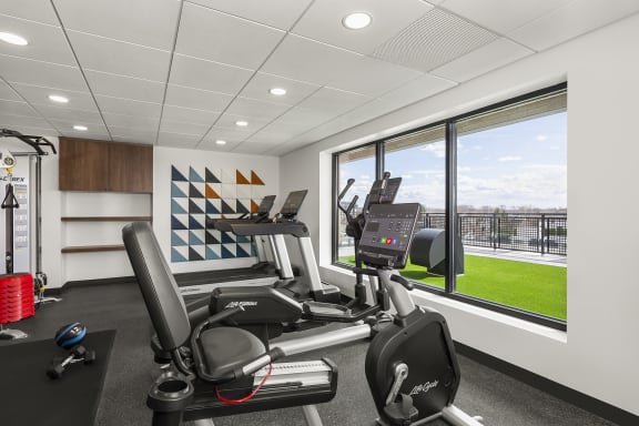 an exercise room with treadmills and a window overlooking the grass