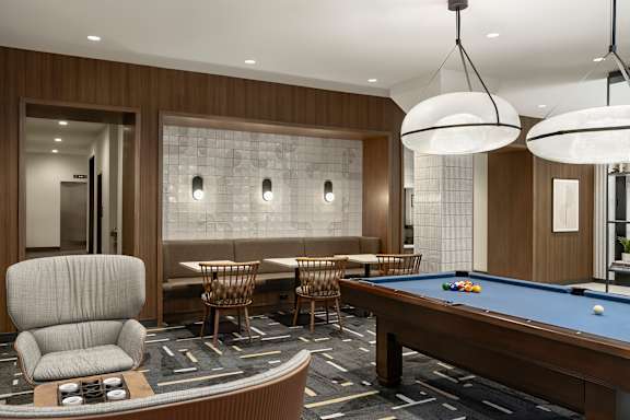Pool table is surrounded by chairs in a room with a wood panelled wall at Arcata Apartments, Golden Valley, Minnesota