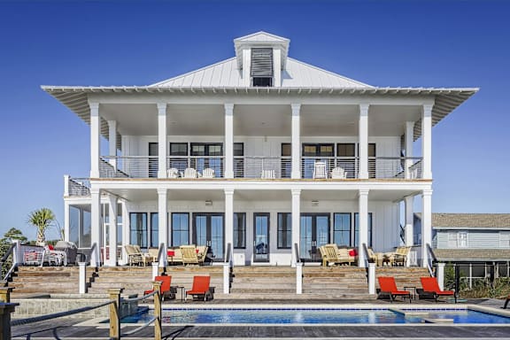 A white house with a pool in front.