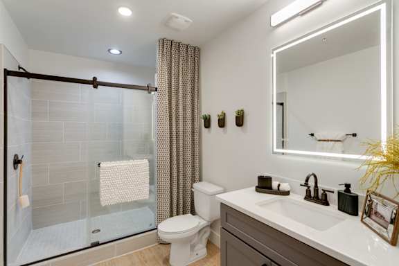 A bathroom with a white toilet, sink, and a shower with a glass door.