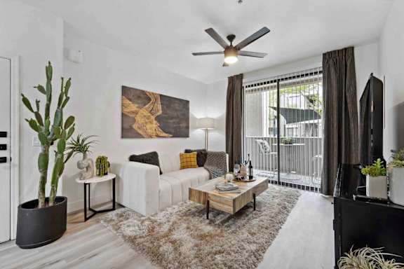 A living room with a white couch, a wooden coffee table, and a large painting on the wall.