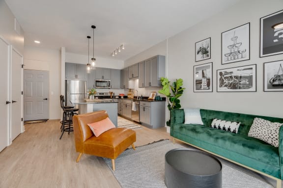 a living room with a green couch and a kitchen in the background