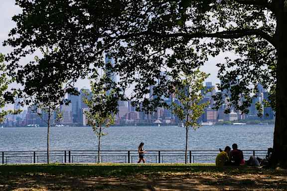 A couple is sitting on the grass by the water. at Aria, New York, 10038