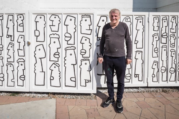 a man standing in front of a wall with a drawing of people
