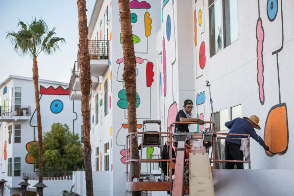 two men working on a building with palm trees