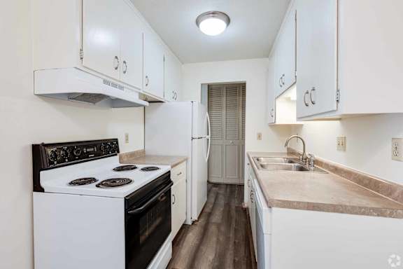 A kitchen with white cabinets and a black stove top.