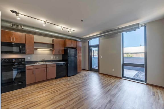 an empty living room with a kitchen and a sliding glass door
