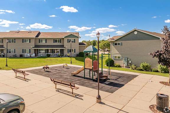 A playground area with a slide and benches in front of a building.