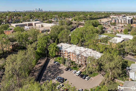 A parking lot is surrounded by trees and buildings.
