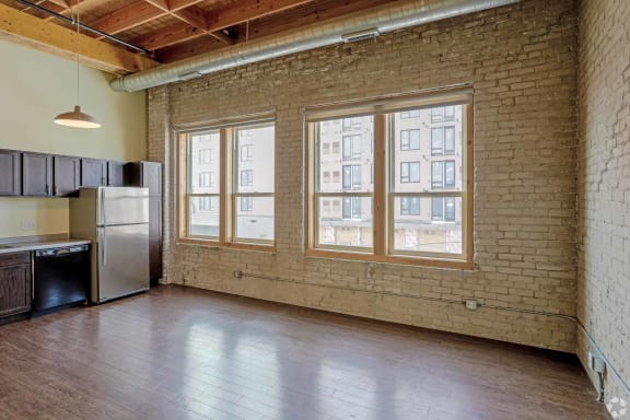 an empty living room with brick walls and a large window
