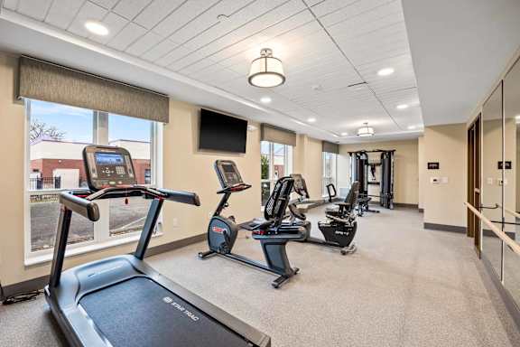 A gym with treadmills, elliptical machines, and a television.