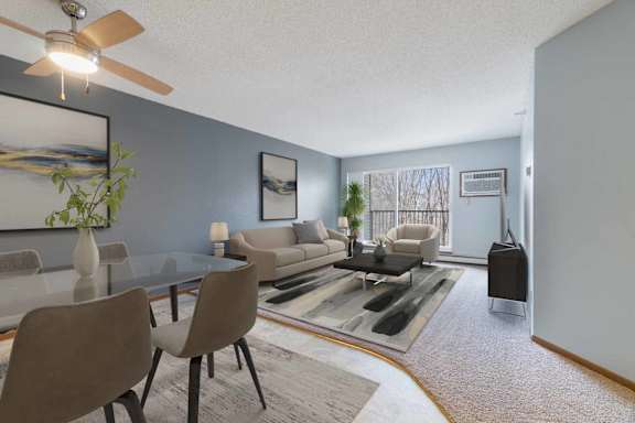A living room with a glass table and grey chairs.