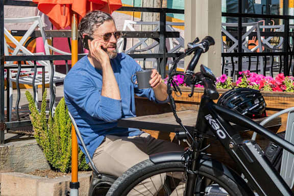 A man in a blue shirt is sitting at a table with a bicycle parked next to him.