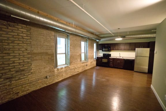 an empty room with wood floors and brick walls