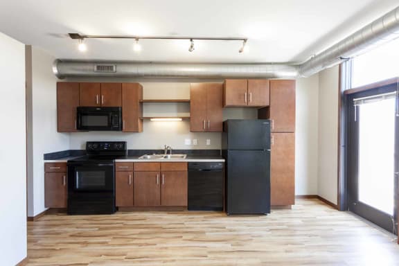 an empty kitchen with wooden cabinets and black appliances