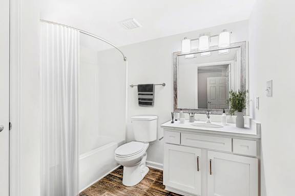 A white bathroom with a toilet, sink, and mirror.