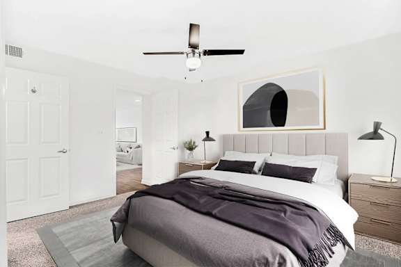 A bedroom with a bed, nightstand, and a ceiling fan.
